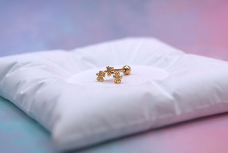 Gullfarget piercingøredobb med blomsterdesign